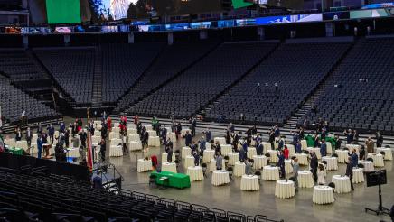Assemblymembers standing at tables in Golden 1 Arena being sworn in