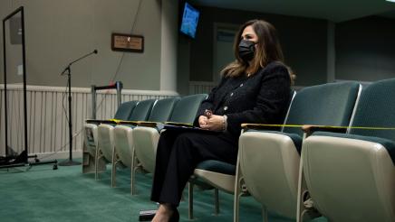 Assemblymember Lisa Calderon sitting in the front row of the seating area in the hearning chambers
