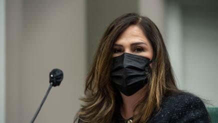 Closeup of Assemblymember Lisa Calderon with a mask on looking at the camera and sitting next to the microphone